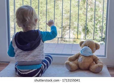 Kind in Hausquarantäne, das mit seinem kranken Teddybär im Fenster spielt und eine medizinische Maske gegen Viren während des Ausbruchs von Coronavirus und Grippe trägt. Kinder und Krankheit COVID-2019 Krankheitskonzept