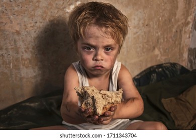 Child Homeless, Beggar Holds A Piece Of Black Bread (concept Of War, Poverty, Crisis). Focus On Bread.