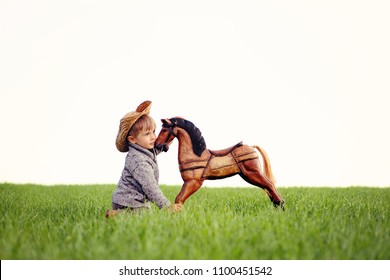 Child And Horse. A Boy, Three Years Old, Playing His Toy Rocking Horse, Dreaming About A Real Horse. A Concept Of True Friendship And Selfless Love. Happy Childhood In The Countryside.