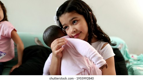 Child hugging black doll, hispanic little girl kid embracing baby black doll