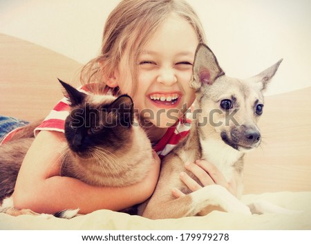 child hugging a cat and dog 