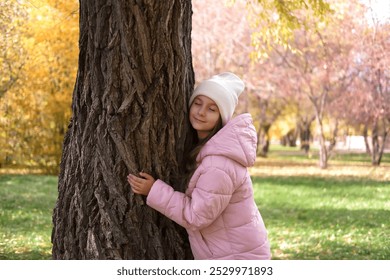 Child hugging a tree in forest on sunny autumn day, symbolizing deep connection with nature and an exciting sense of calm in natural world. Lifestyle, environmentalism. - Powered by Shutterstock