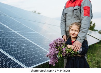 The child hugs the dad the electrician, on a background of solar panels. The engineer shows the girl the future of alternative energy and sustainable energy. The concept of ecology, a happy future. - Shutterstock ID 1745496206