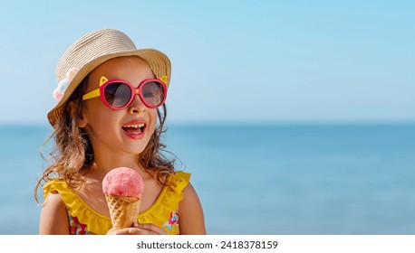 A child with an ice cream ball in a conical cup against the background of the blue sea. Enjoying a cool treat in hot weather. The child is on vacation on a trip. - Powered by Shutterstock