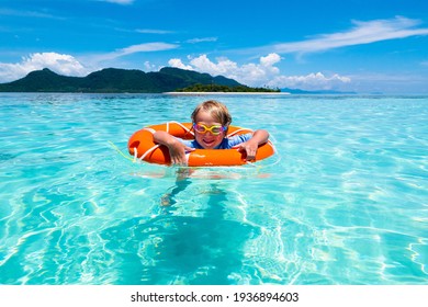 Child With Inflatable Ring On Beautiful Beach. Little Boy Swimming In Exotic Sea. Ocean Vacation With Kid. Children Play On Summer Beach. Water Fun. Kids Swim. Family Holiday On Tropical Island.