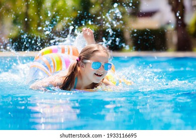 Child With Inflatable Toy Ring Float In Swimming Pool. Little Girl Learning To Swim And Dive In Outdoor Pool Of Tropical Resort. Swimming With Kids. Healthy Sport Activity For Children. Water Fun.