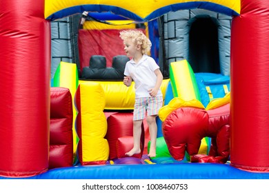 Child jumping on colorful playground trampoline. Kids jump in inflatable bounce castle on kindergarten birthday party Activity and play center for young child. Little boy playing outdoors in summer. - Shutterstock ID 1008460753