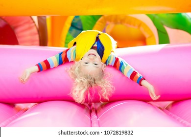 Child jumping on colorful playground trampoline. Kids jump in inflatable bounce castle on kindergarten birthday party Activity and play center for young child. Little boy playing outdoors in summer. - Shutterstock ID 1072819832