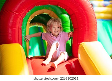 Child jumping on colorful playground trampoline. Kids jump in inflatable bounce castle on kindergarten birthday party Activity and play center for young child. Little boy playing outdoors in summer. - Powered by Shutterstock