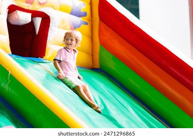 Child jumping on colorful playground trampoline. Kids jump in inflatable bounce castle on kindergarten birthday party Activity and play center for young child. Little boy playing outdoors in summer. - Powered by Shutterstock