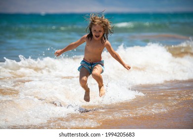 Child jumping on ocean beach. Kid jump in the waves at sea vacation. Little boy running on tropical beach of exotic island during summer holiday. - Powered by Shutterstock