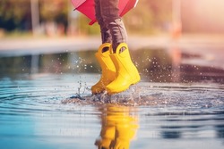 Child Jumping In The Puddle In Yellow Rubber Boots