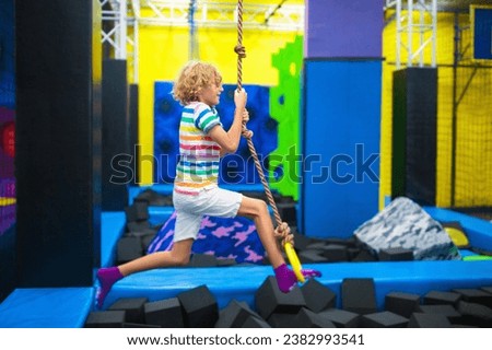 Child jumping in trampoline park. Bounce fun on kids birthday party. Indoor playground with bouncing castle. Healthy activity for children. Fit kid exercising and playing on colorful trampolines.