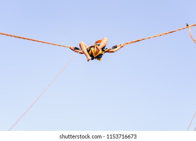 Child Jumping Very High In Elastic Trampoline , Seen From Below And Unrecognizable.