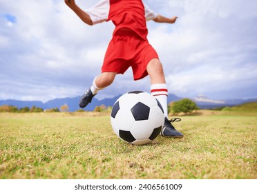 Child, kicking and soccer ball on green grass for sports, training or practice with clouds and blue sky. Closeup of football player foot ready for kick off, game or match on outdoor field in nature - Powered by Shutterstock