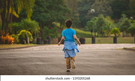 Child, Kid, Boy In Blue Shirt, Brown Pants, Jeans Jacket On Waist, Running Away Lonely In Park, Greenery