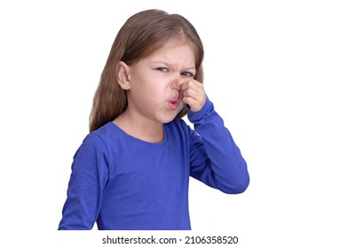 Child Kid Holding Fingers On Nose Showing That Bad Smell, Isolated On White Background Looking At Camera Waist Up Caucasian Little Girl Of 5 Years In Blue