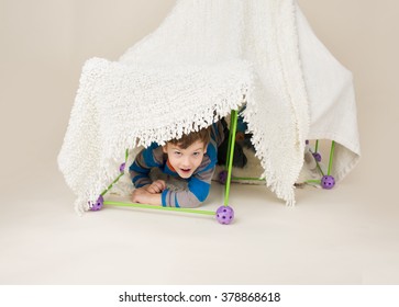 Child, kid, playing with a tent or fort made out of blankets