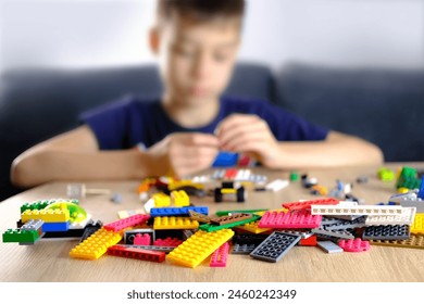 child, kid plays with colored plastic parts of the constructor, creates buildings, equipment, transport, the concept of the development of creativity, fine motor skills, patience and perseverance - Powered by Shutterstock