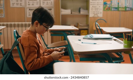 Child kid son pupil student bad behavior boy schoolboy playing video game on mobile phone at lesson at school hide smartphone under class desk distract from studying gadget addiction writing learning - Powered by Shutterstock