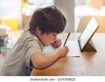 Child kid using tablet for homework at home,Student study research information online internet,Education Ai Technology,Asian Young Boy Concentration read and writing on notepad book,Preschool lesson - Shutterstock ID 1676706823