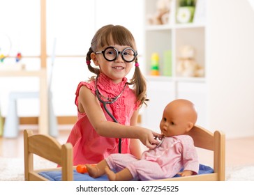 Child in kindergarten. Kid in nursery school. Little girl preschooler playing doctor with doll. - Powered by Shutterstock