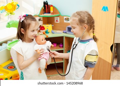 Child in kindergarten. Kids in nursery school. Girl playing with doll at infant school