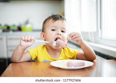 child in the kitchen eating sausage and mashed potatoes - Shutterstock ID 1177927606