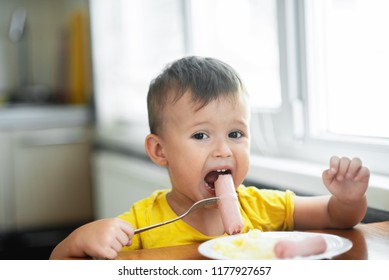 Child In The Kitchen Eating Sausage And Mashed Potatoes