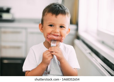 The Child In The Kitchen Eating Sausage And Mashed Potatoes On Their Own