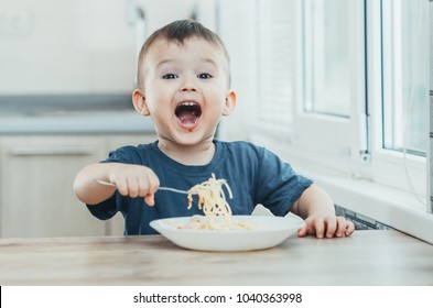 The child in the kitchen at the table eating macaroni and interesting view from the top