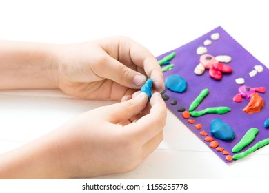 A child kneads plasticine and sculpts an aquarium with fish. Tutoring with children.