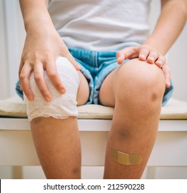 Child Knee With Adhesive Bandage, Bruise And Gauze Bandage.