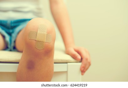 Child knee with an adhesive bandage and bruise.