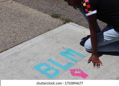 Child Kneeling Near BLM Blaack Lives Matter Words On Sidewalk