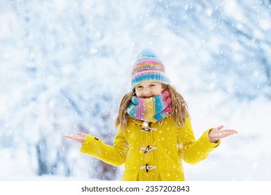 Child in knitted hat playing in snow on Christmas vacation. Winter outdoor fun. Knitting and outerwear for family. Kids play in snowy park. Little girl in knit scarf and mittens catching snowflakes. - Powered by Shutterstock