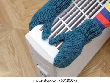 Child In Knitted Mittens Touching Heating Electric Radiator.