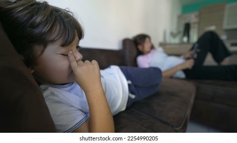 Child laying on sofa at home rubbing eye with finger. Tired young boy relaxing on couch while touching face with hand - Shutterstock ID 2254990205