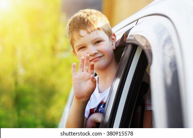 Child Leaned Out The Window Of A Car And Waving His Hand.