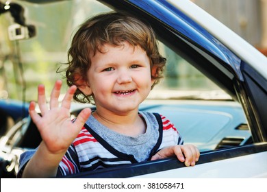 Child Leaned Out The Window Of A Car And Waving His Hand.