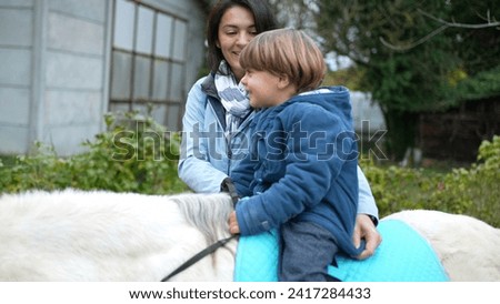 Child leaning on park swing on his stomach outside during autumn fall season day, kid wearing blue jacket