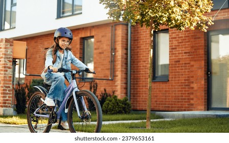 Child learning to drive a bicycle on a driveway outside. Little girl riding bikes on asphalt road in the city wearing helmets as protective gear. - Powered by Shutterstock