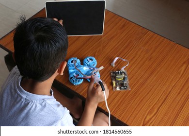 A Child Learning To Make Online Electric Drone. Tab Screen Black. A Child Tabs That Screen While Zooming. Concept Online Kids Coding Classes