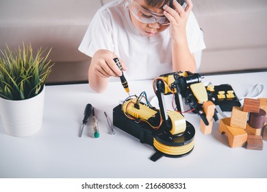 Child Learning Repair Getting Lesson Control Robot Arm, Happy Asian Little Kid Boy Using Screwdriver To Fixes Screws Robotic Machine Arm In Home Workshop, Technology Future Science Education Concept