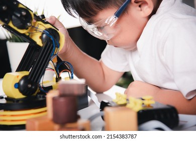 Child Learning Repairing Getting Lesson Control Robot Arm, Happy Asian Little Kid Boy Using Screwdriver To Fixes Screws Robotic Machine Arm In Home Workshop, Technology Future Science Education