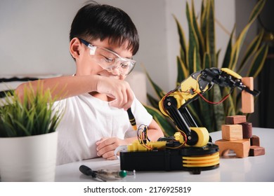 Child Learning Repairing Getting Lesson Control Robot Arm, Happy Asian Little Kid Boy Using Screwdriver To Fixes Screws Robotic Machine Arm In Home Workshop Technology Future Science Education Concept