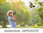 Child learning to take photos. Kid photographer. Little boy watching birds and making images with professional camera. Parent teaching son to photograph wildlife. Young creative artist.