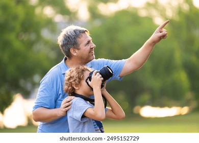 Child learning to take photos. Kid photographer. Little boy watching birds and making images with professional camera. Parent teaching son to photograph wildlife. Young creative artist. - Powered by Shutterstock