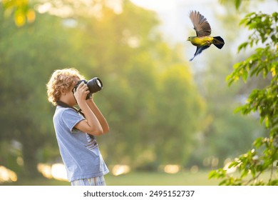 Child learning to take photos. Kid photographer. Little boy watching birds and making images with professional camera. Parent teaching son to photograph wildlife. Young creative artist. - Powered by Shutterstock