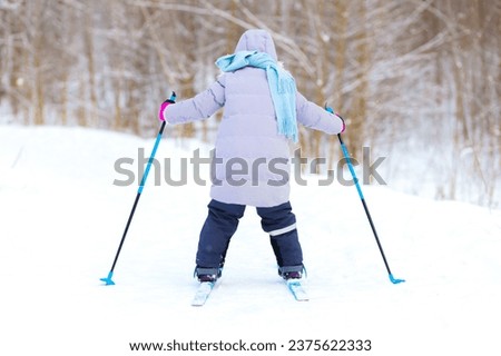 child learning training to ski in winter. Active winter sports for children. little skier racing in snow on forest track. girl on cross-country skis. skiing kid